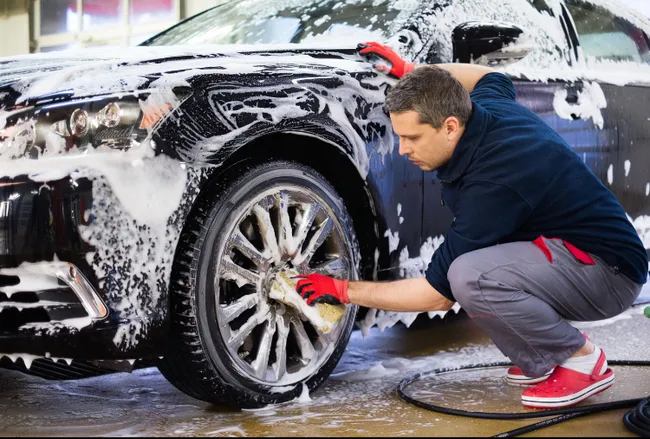 A man is polishing the windshield of a car